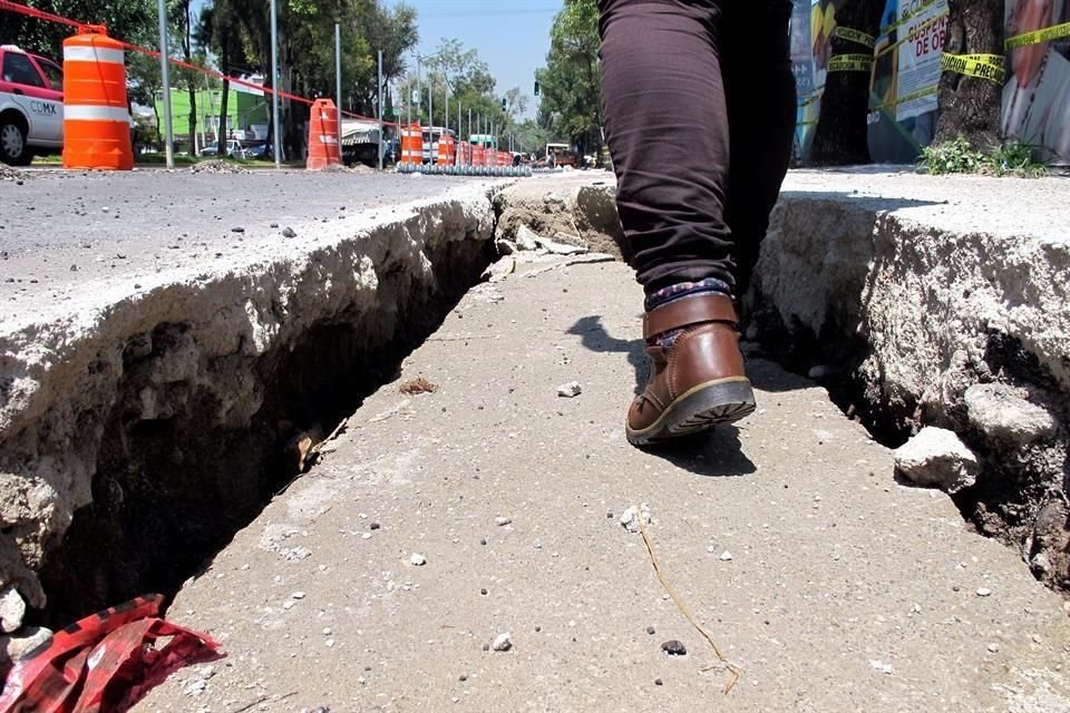 Sobre el arroyo vehicular se puede apreciar la falla en el suelo que sigue la línea en paralelo del perímetro de la obra y se ven capas de concreto superpuestas para tapar la cavidad.