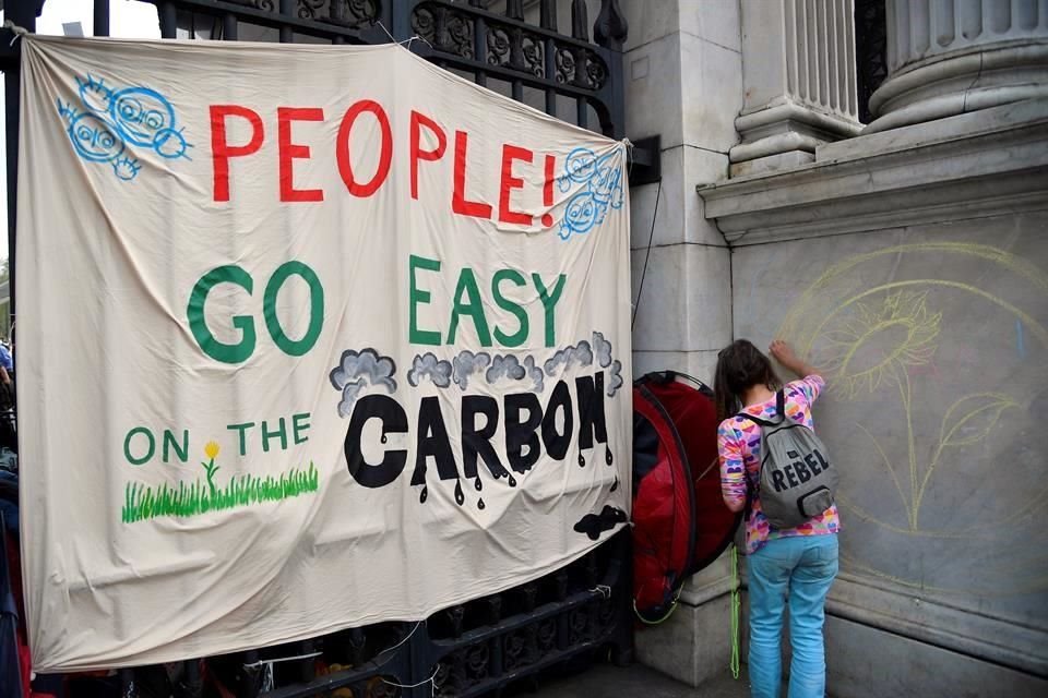 Una mujer del grupo Extinction Rebellion dibuja un lema político en una protesta sobre cambio climático en Londres.