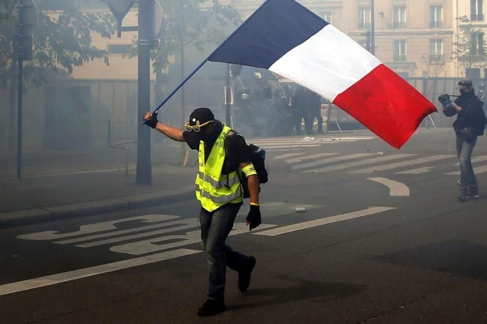 Un manifestante agita una bandera francesa lejos del contingente de la marcha.