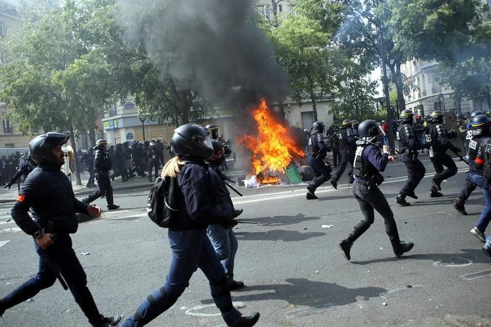 Policías corren hacia manifestantes durante la protesta.