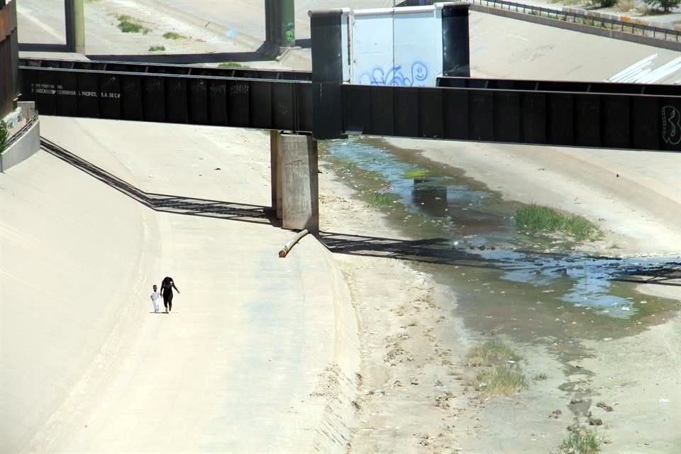 Padres con sus hijos corren para llegar a la valla fronteriza.