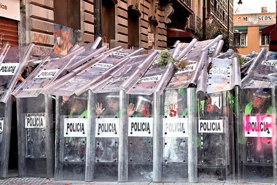 Policías se protegían detras de sus escudos.