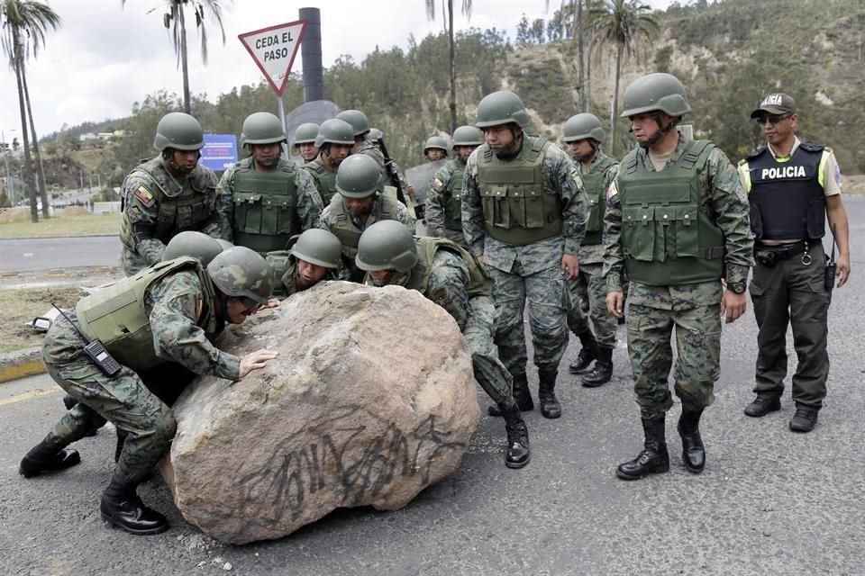 Soldados, desplegados tras una orden presidencial la semana pasada, intentan remover una piedra de la vía Simón Bolivar, en Quito.