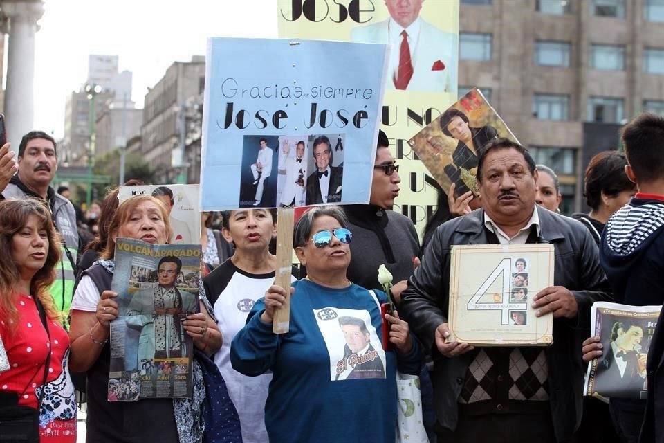 Fanáticos del cantante mexicano José José portan pancartas y fotos del cantante.