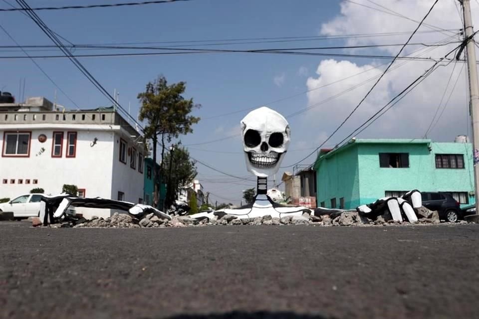 Inspirados en los 'eternos' baches en sus calles y la leyenda del Mictlán, vecinos de Tláhuac colocaron calaveras monumentales que 'emergen' del pavimento, en la Colonia Santa Cecilia.