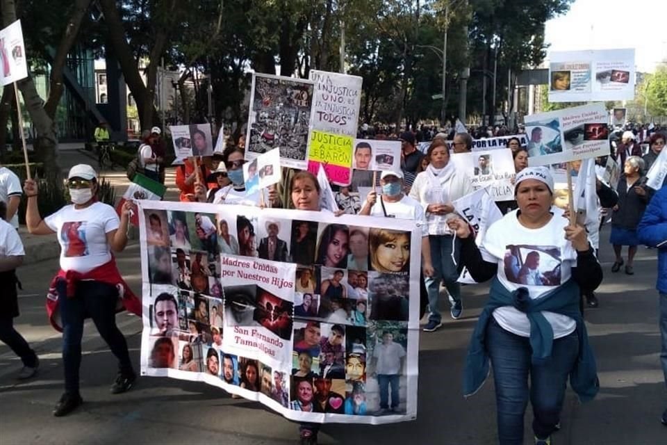 Ciudadanos cargan mantas con las fotografías de sus familiares desaparecidos.