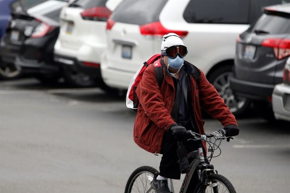 Una persona usando un cubrebocas maneja una bicicleta en el Centro del cuidado de la vida de Kirkland, mismo que ha sido vinculado con varios casos confirmados de coronavirus.