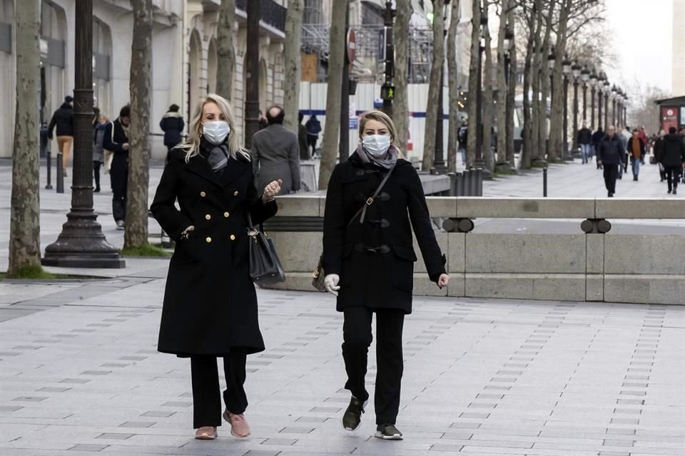 Turistas usan cubrebocas mientras pasean por los Campos Elíseos, en París, Francia.