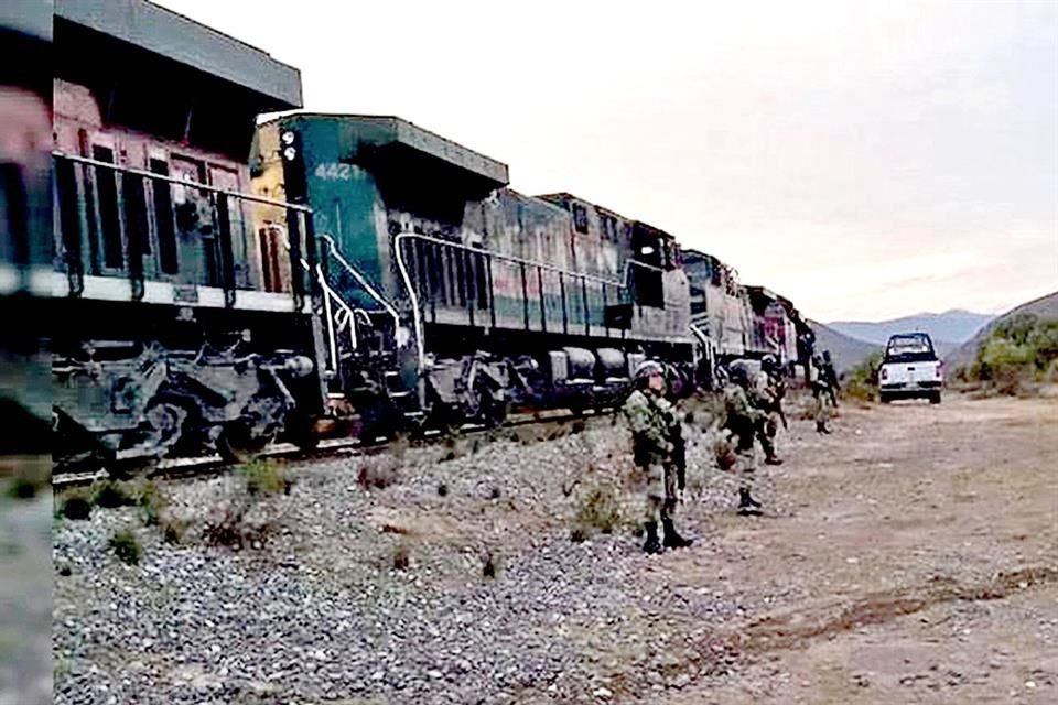 Elementos resguardan el ferrocarril para evitar actos de rapiña mientras el tren no puede avanzar.