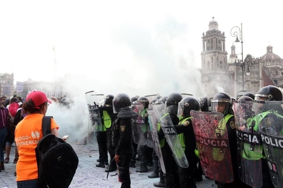 Ante las agresiones, las elementos de la agrupación Atenea de la policía capitalina se cubren con sus escudos y con cascos.