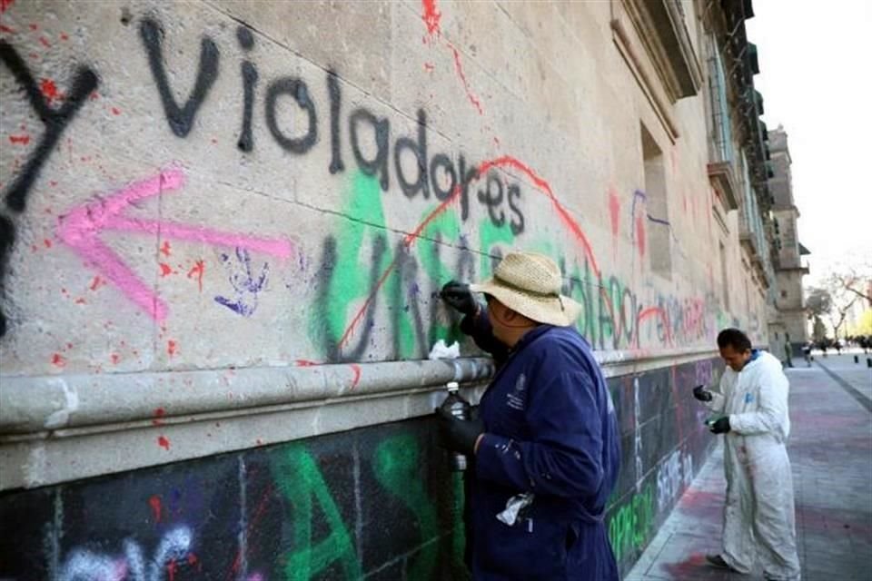 Trabajadores federales iniciaron la limpieza de la fachada de Palacio Nacional que ayer fue pintada con aerosol y pintura con consigas contra la violencia de género.