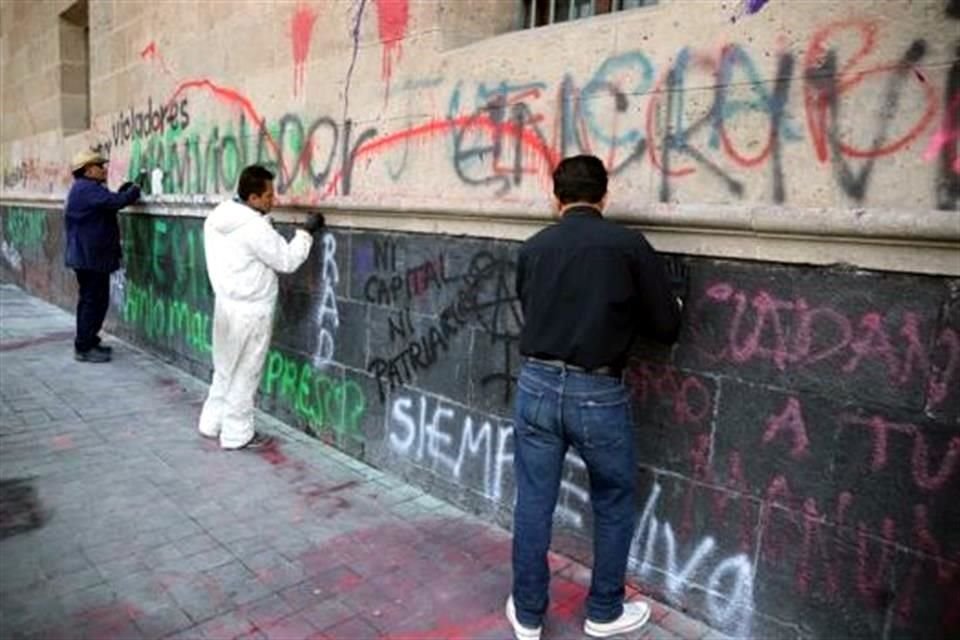 Trabajadores federales iniciaron la limpieza de la fachada de Palacio Nacional que ayer fue pintada con aerosol y pintura con consigas contra la violencia de género.