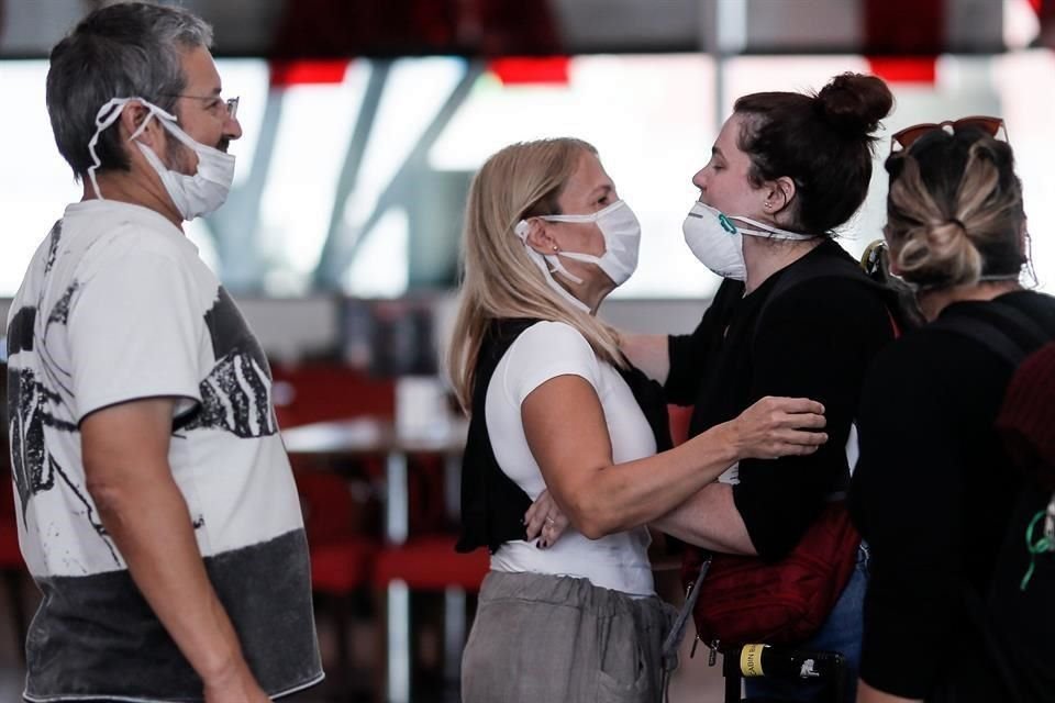 Pasajeros usan cubrebocas para protegerse del coronavirus mientras transitan por el Aeropuerto Internacional de Ezeiza, en Buenos Aires.