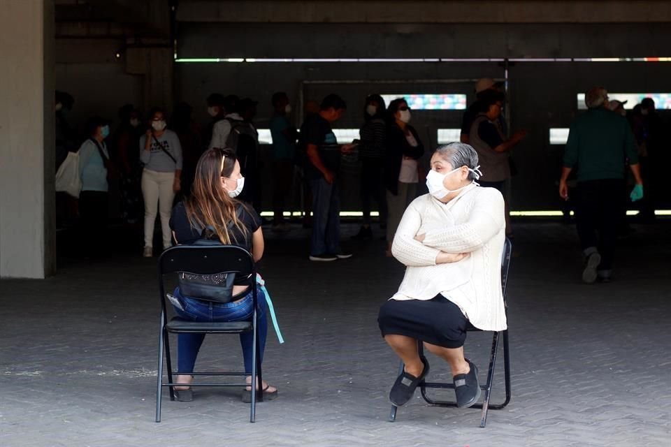 Dos mujeres conversan mientras esperan en la jornada de vacunación contra la influenza en el Estadio Bicentenario de la Florida el sábado, en Santiago.