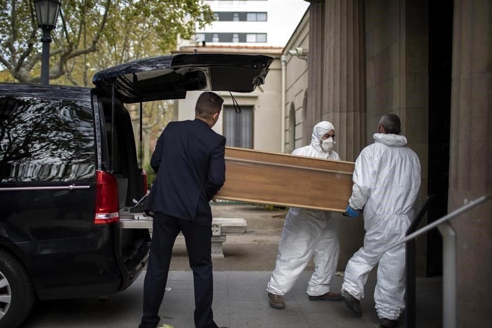 Trabajadores cargan un ataúd de una víctima del Covid-19 en España.