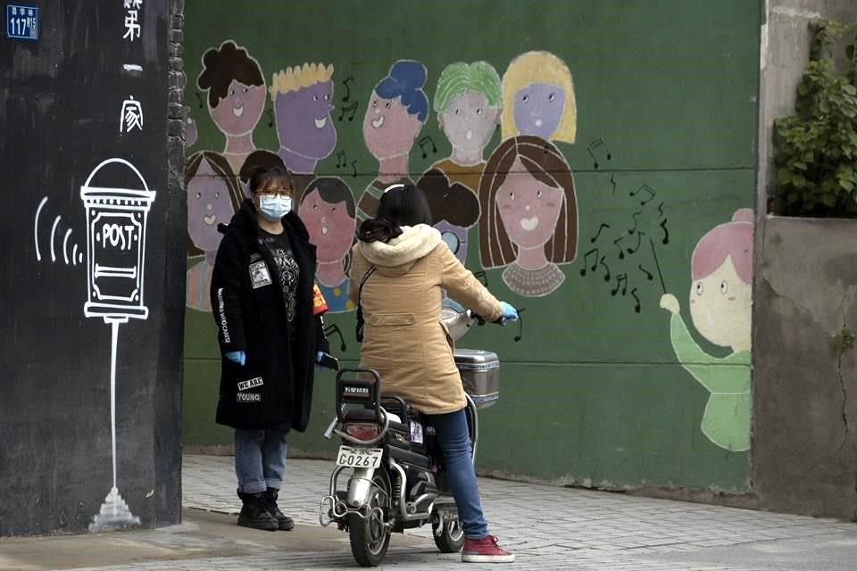 Dos personas hablan en Wuhan, China, lugar del primer brote.