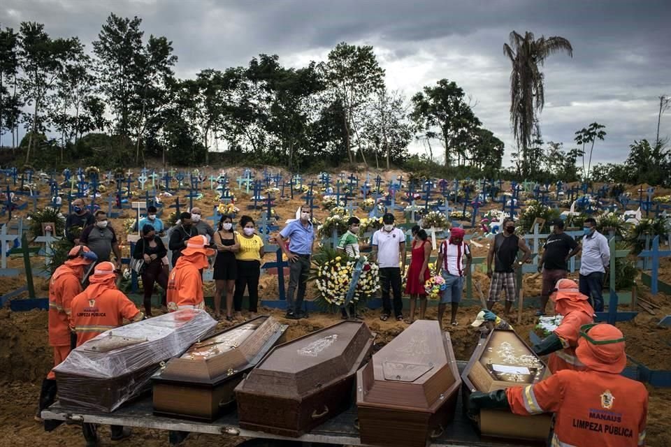 Un grupo de personas asiste a un sepelio en una tumba colectiva, el 23 de abril de 2020, en un área abierta en el cementerio Nossa Senhora Aparecida, ubicado en la ciudad de Manaos, Amazonas.