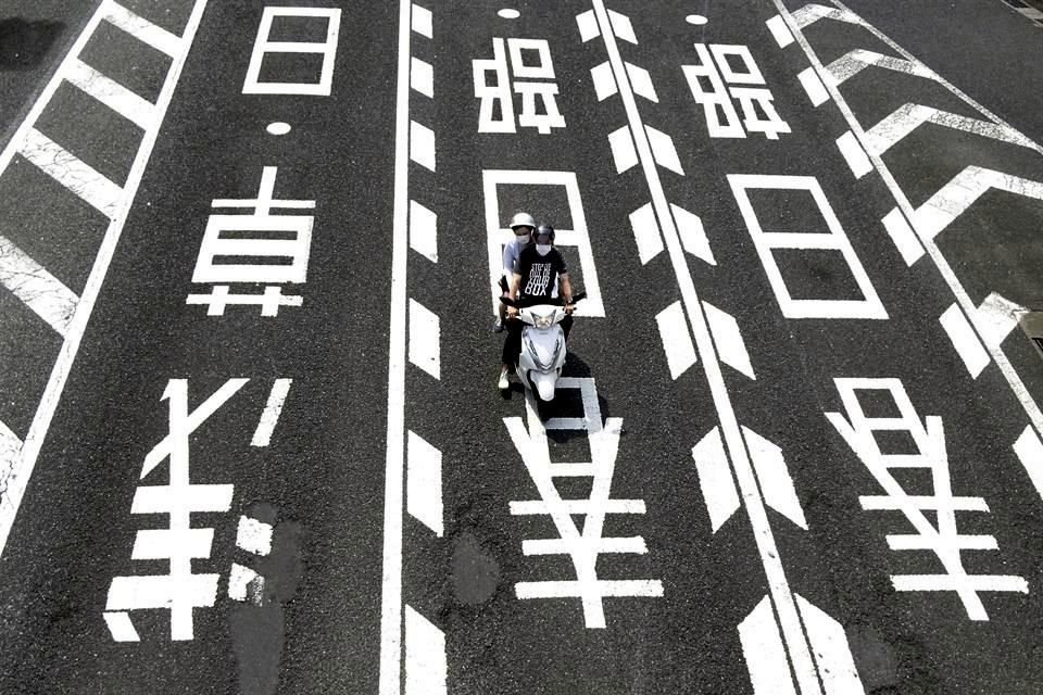 Dos personas usan cubrebocas durante un viaje en motocicleta en Tokio, Japón.