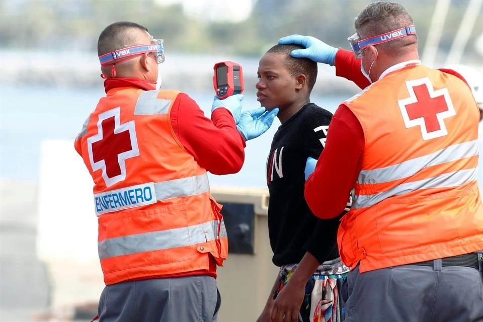 Miembros de la Cruz roja le toman la temperatura a un migrante en costas de España.