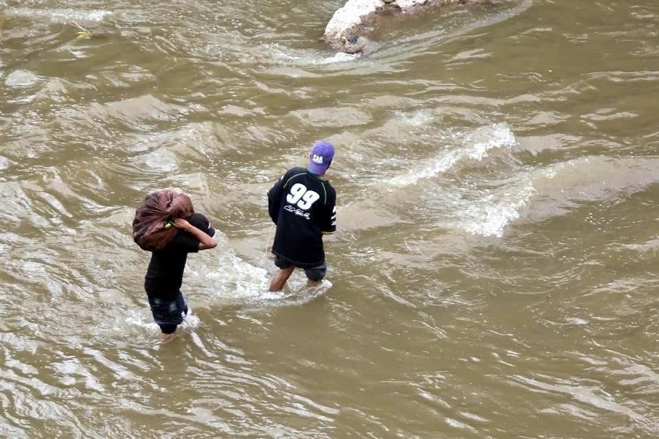 Fotografía fechada el 30 de mayo de 2020 que muestra a ciudadanos hondureños mientras cruzan un río con el caudal alto, en Tegucigalpa.