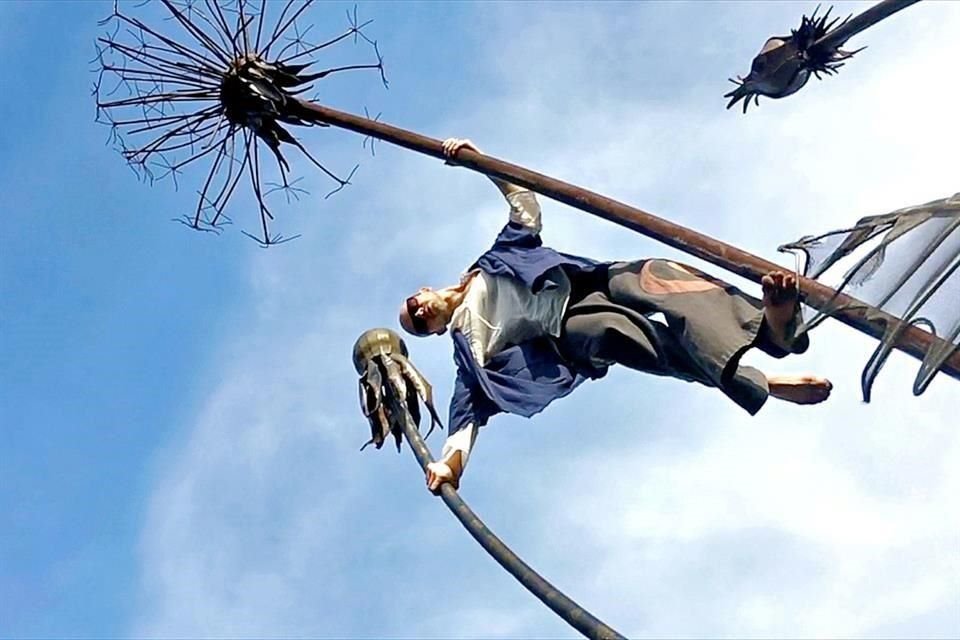 Grouss se desplaza alrededor de una escultura monumental de Vitaly Altabaev con forma de diente de león, que evoca a la del virus; un recordatorio de la presencia 'omnipresente' del Covid-19.