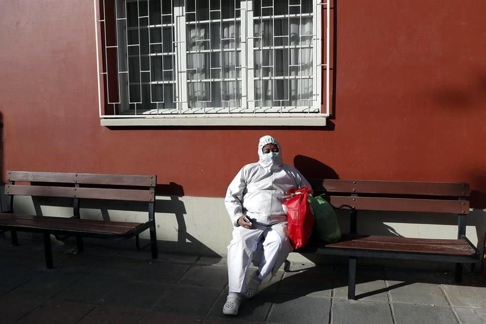 Una enfermera con un traje protector descansa afuera del Hospital General de La Paz.