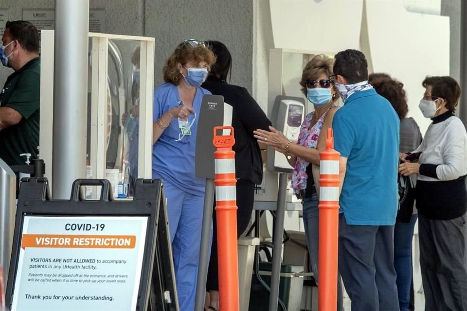 Personas en Miamia hace fila usando cubrebocas para entrar a un hospital.