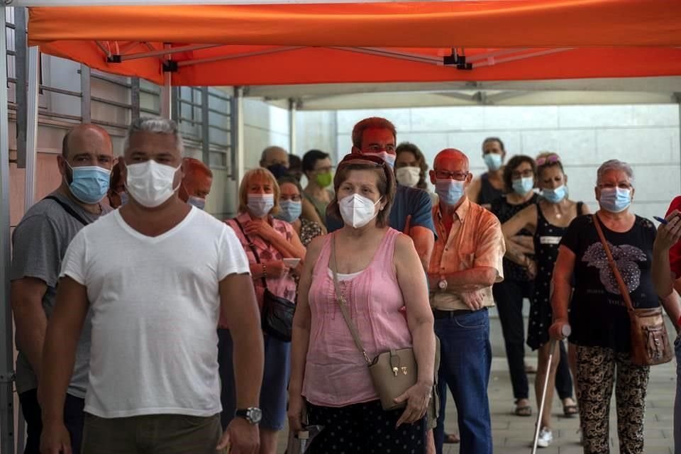 Personas en Barcelona hacen fila con cubrebocas para realizarse pruebas de coronavirus.