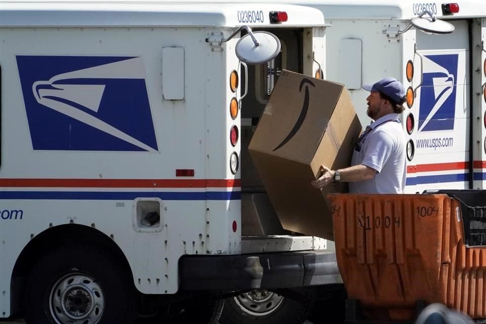 Un trabajador carga un paquete de Amazon en un camión del Servicio Postal.