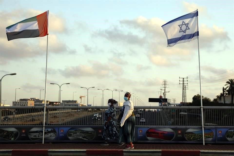 Dos mujeres caminan bajo banderas de Emiratos Árabes Unidos e Israel, en el Puente de la Paz, en Netanya, Israel.