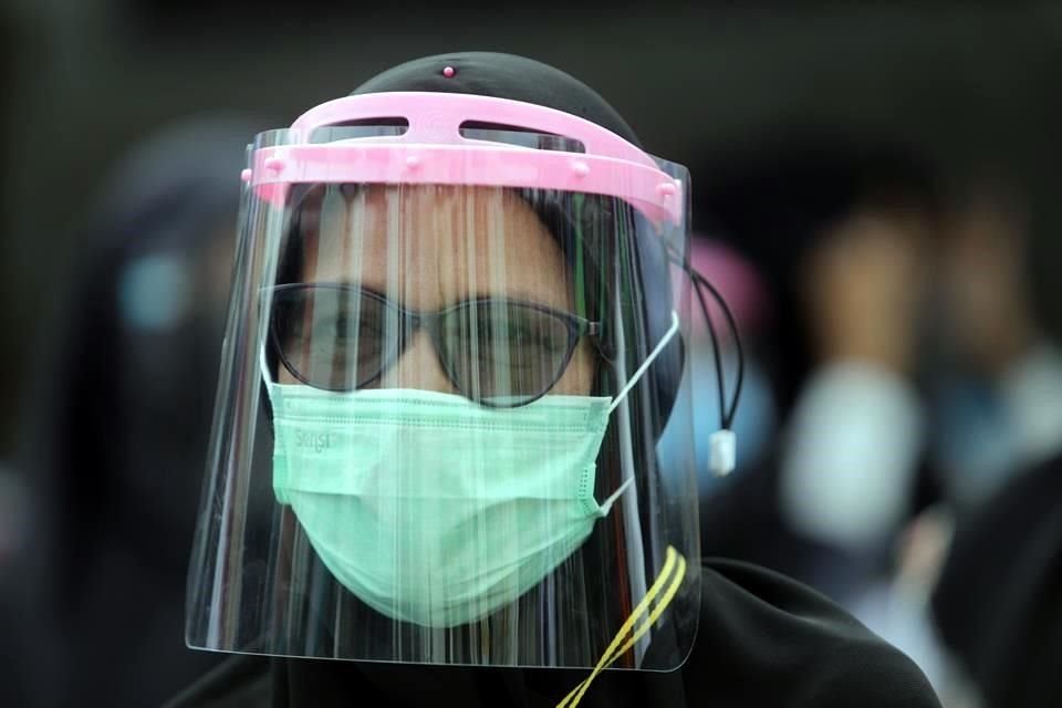 Una mujer en Indonesia lleva mascarilla y encima una careta protectora.