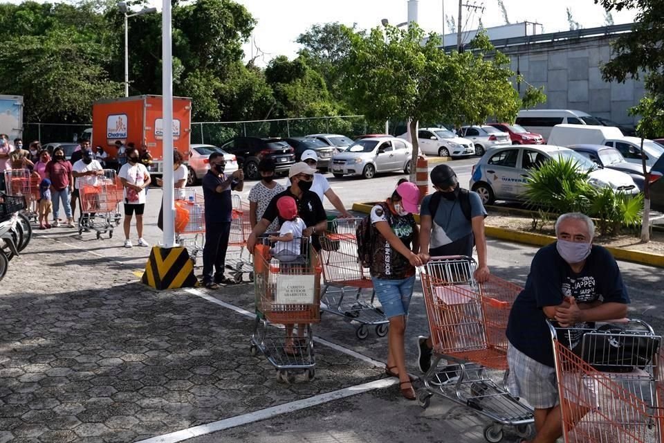 Personas se forman para ingresar a un supermercado previo a la llegada del huracán Delta en Puerto Morelos.