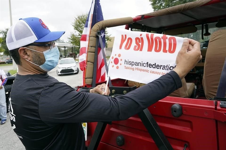 Un hombre cuelga una bandera de la organización Hispanic Federation para promover el voto latino.