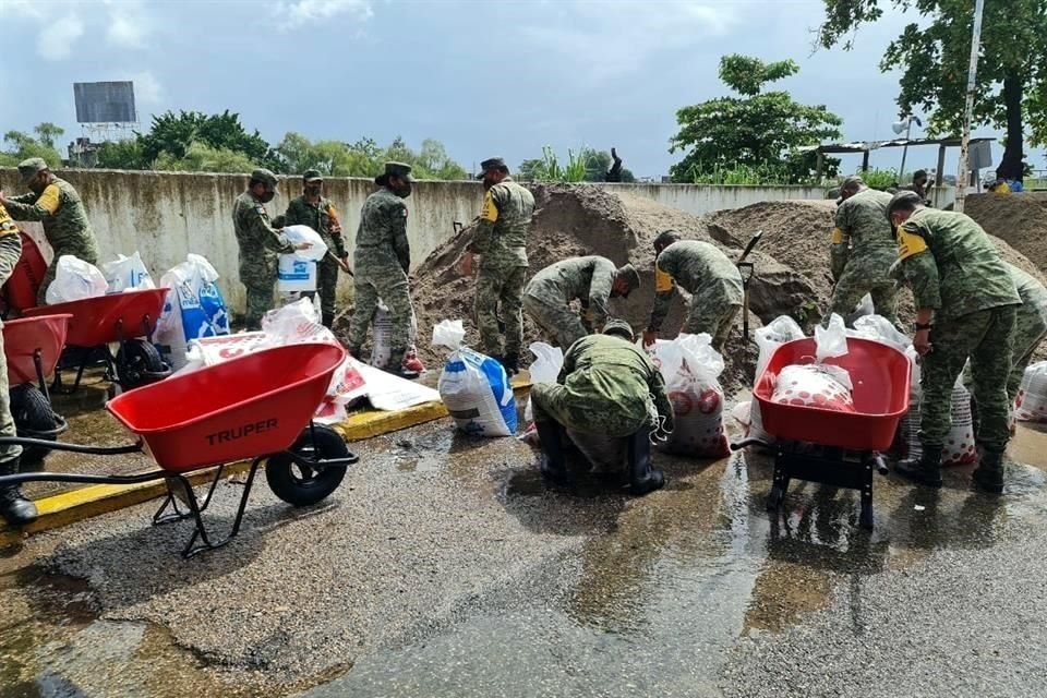 Elementos del ejército ayudan a colocar costales con tierra en las orillas del Río Grijalva.