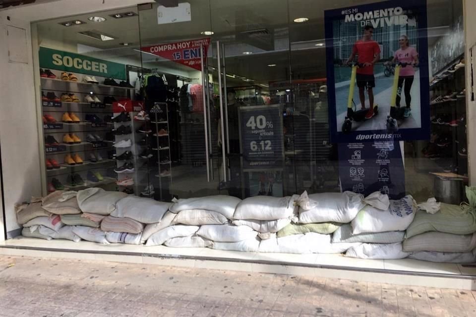 Comercios colocan costales a las entradas de sus locales para evitar que el agua del Grijalva se filtre al interior.