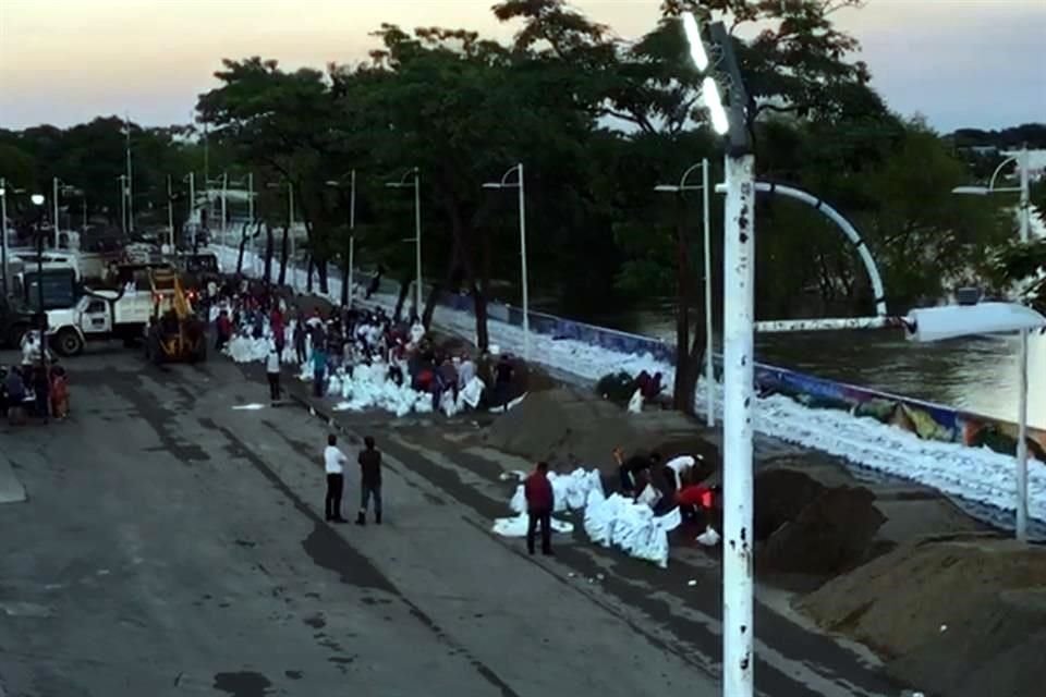 Personal del Ejército y ciudadanos refuerzan con costales de arena el Río Grijalva.