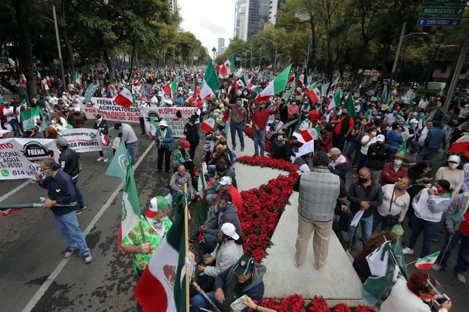 Los asistentes a la marcha caminan con banderas de México en la mano.