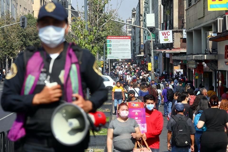 Un policía vigila uno de los filtros sanitarios mientras una gran cantidad de gente pasa a su lado en el Centro Histórico.