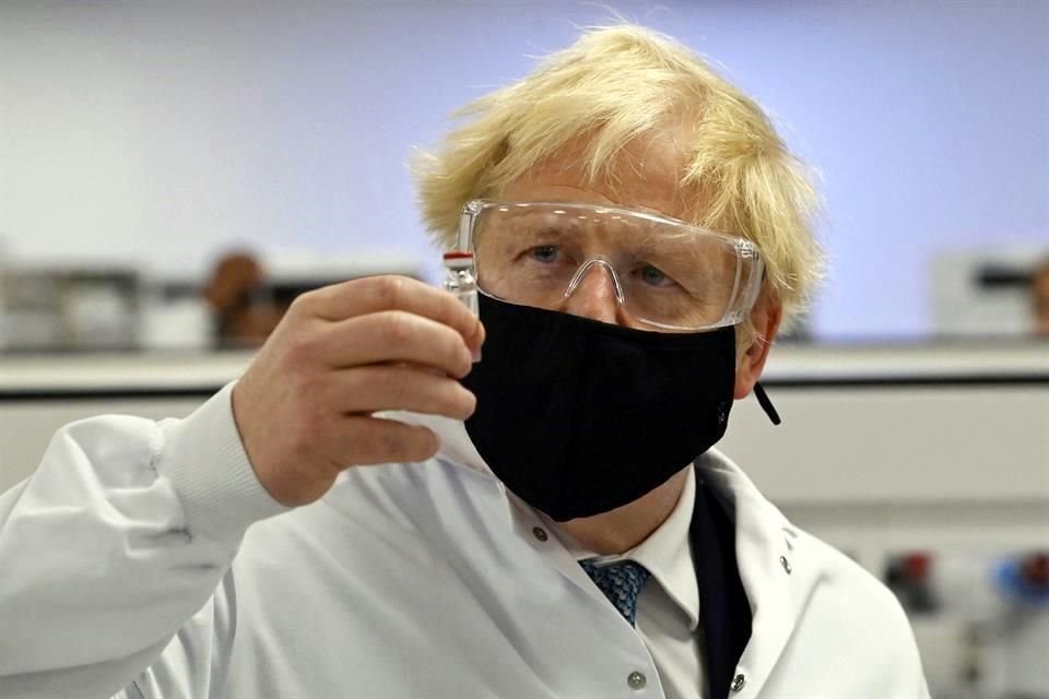 El Primer Ministro de Reino Unido, Boris Johnson, examina un vial con la vacuna contra Covid-19 de Oxford y AstraZeneca.