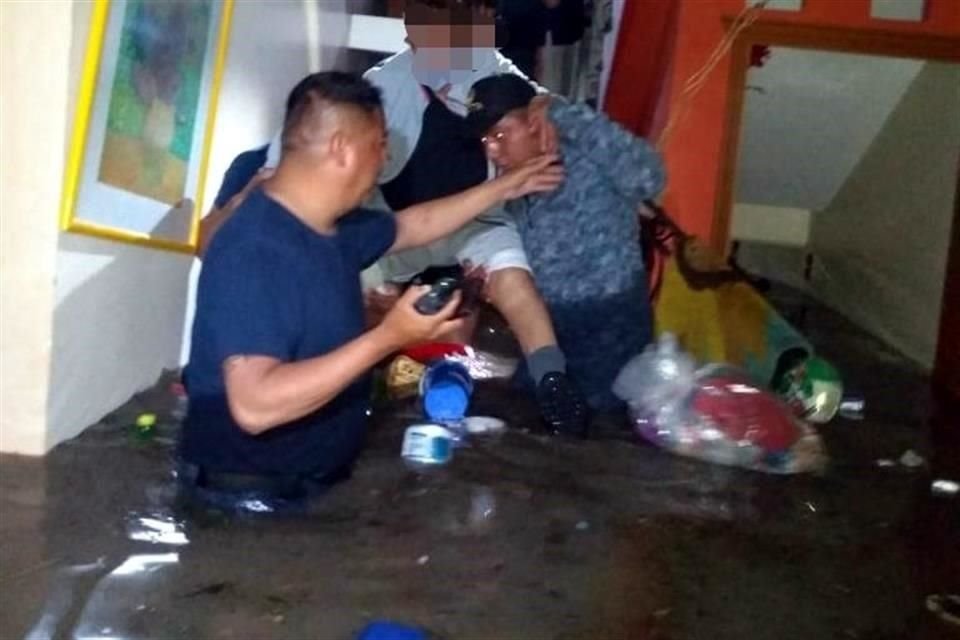 Autoridades ayudan en labores de rescate a personas afectadas por inundaciones.