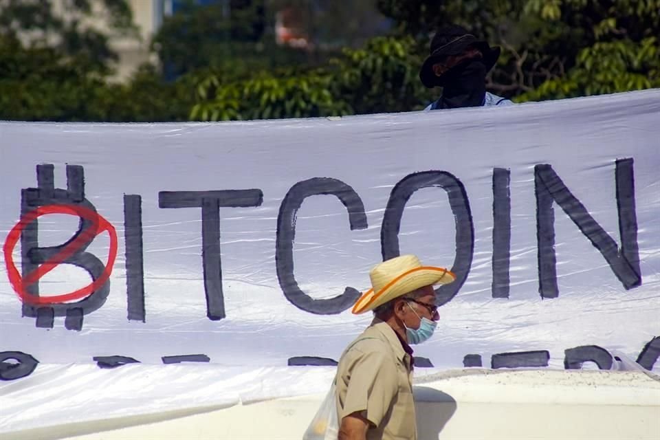 Un hombre camina frente a una pancarta colocada durante una protesta en contra de la entrada en vigor de la llamada 'Ley Bitcoin', que desde el martes es una moneda de curso legal en El Salvador.