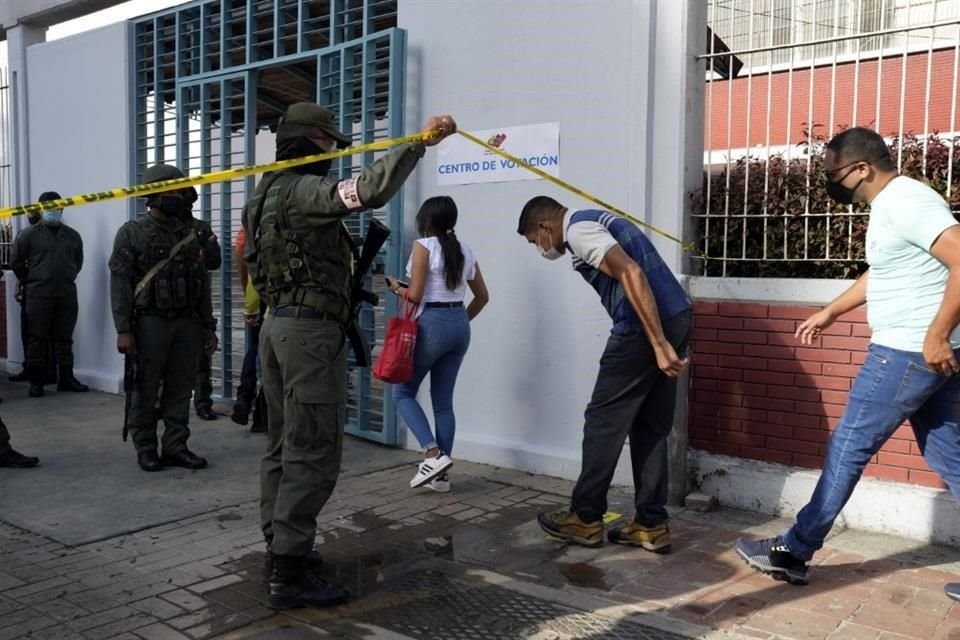 Personal de seguridad permite la entrada a una casilla electoral de Caracas a ciudadanos.