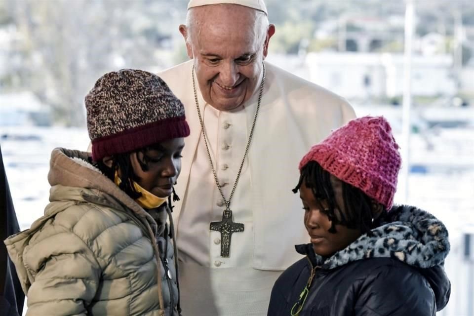 El Papa Francisco saluda a dos refugiados durante su visita a un campamento de migrantes en Lesbos.