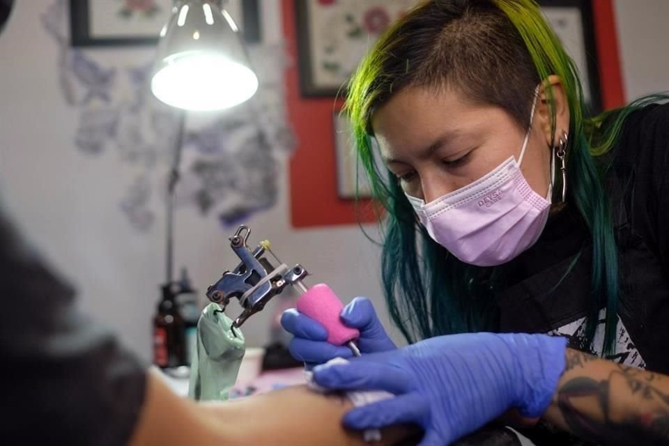 La tatuadora chilena Yumbel Góngora trabaja en el brazo de un cliente en su estudio en Santiago, Chile, el miércoles 22 de diciembre de 2021.