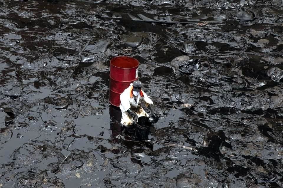 Un trabajador limpia el derrame de petróleo que se registró el sábado durante el proceso de descarga de crudo del buque Mare Dorium luego de un fuerte oleaje, en Perú.