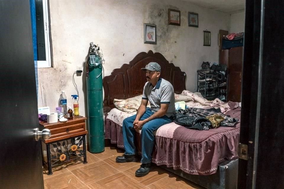 Guillermo Ramírez sentado en su cama luego de un día de trabajo. A un lado hay un tanque de oxígeno, que usa su bebé hospitalizada. 'Es muy poco lo que estás ganando', dijo. 'Te hace sentir impotente'