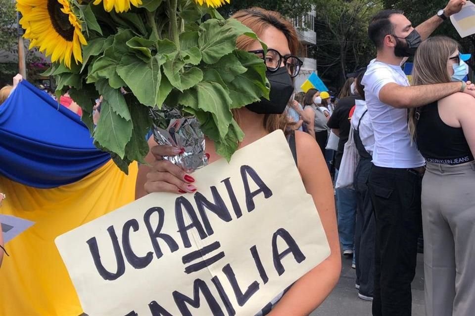 Una mujer lleva un ramo de girasoles con un cartel que afirma 'Ucrania = familia'.