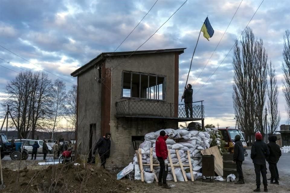 Residentes elevan una bandera ucraniana en un puesto de control en Hushchyntsi.