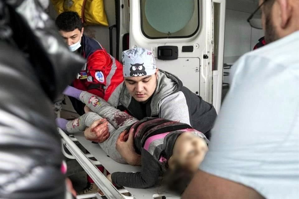 Médicos en Mariupol, en el este de Ucrania, transportan a una niña herida por un bombardeo ruso.