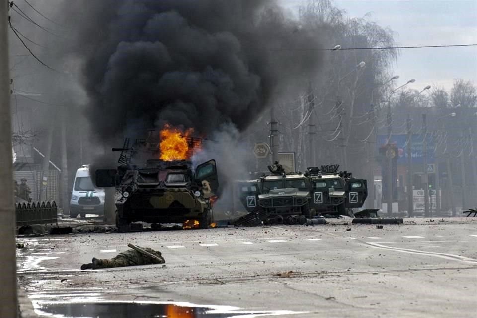 Un vehículo blindado de transporte de personal ruso arde entre vehículos utilitarios ligeros dañados y abandonados después de los combates en Járkov el domingo 27 de febrero de 2022.